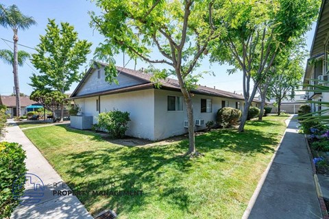 a small white house with a yard and trees
